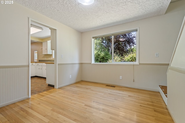 6120 SW Cross Creek Dr, Beaverton, OR 97078 - spare room with light wood-style flooring, a wainscoted wall, and a textured ceiling