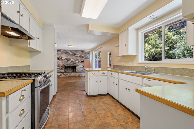 6120 SW Cross Creek Dr, Beaverton, OR 97078 - kitchen featuring stainless steel range with gas stovetop, under cabinet range hood, a fireplace, white cabinets, and a textured ceiling