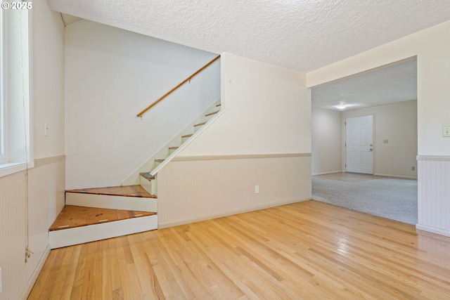 6120 SW Cross Creek Dr, Beaverton, OR 97078 - unfurnished living room featuring wood finished floors, stairway, a textured ceiling, and wainscoting