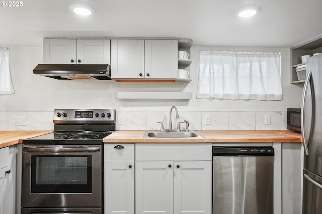 5025 NE 6th Ave, Portland, OR 97211 - kitchen with butcher block counters, stainless steel appliances, under cabinet range hood, a sink, and recessed lighting