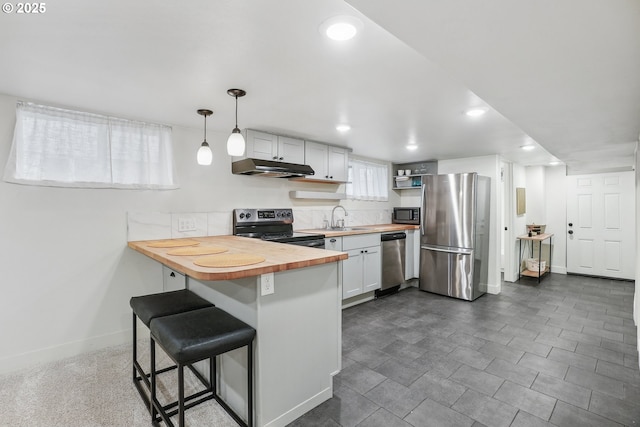 5025 NE 6th Ave, Portland, OR 97211 - kitchen featuring butcher block countertops, appliances with stainless steel finishes, a sink, a peninsula, and open shelves