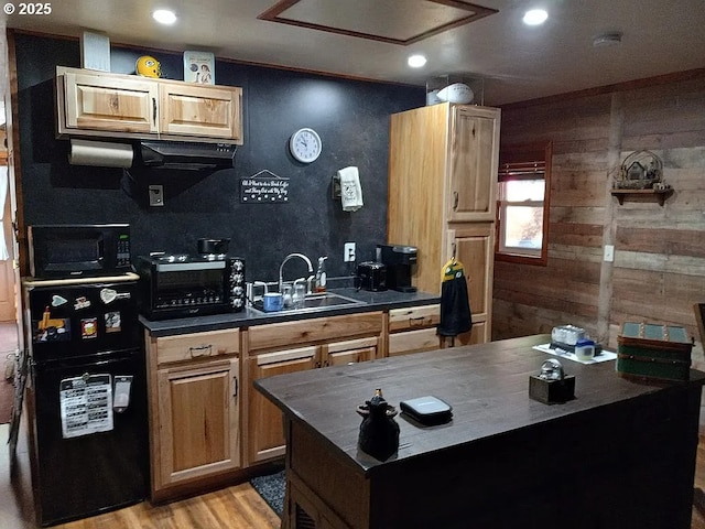 kitchen with a toaster, a sink, light wood-type flooring, black appliances, and dark countertops