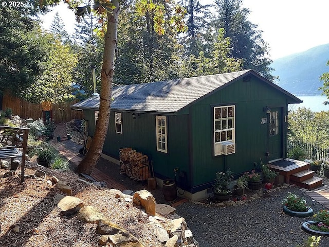 view of home's exterior with an outbuilding, a shingled roof, and fence