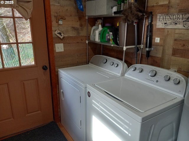 washroom featuring laundry area, wooden walls, and separate washer and dryer