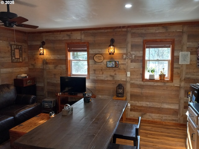 dining space featuring wood finished floors, a ceiling fan, and wooden walls