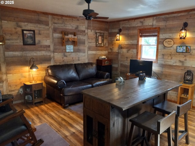 living room with a ceiling fan, wooden walls, and wood finished floors