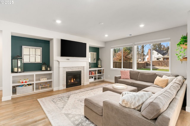 living room featuring a stone fireplace and light hardwood / wood-style flooring