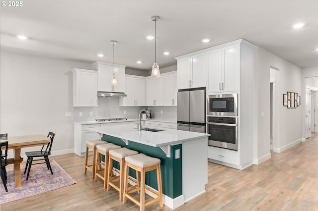 kitchen with pendant lighting, sink, white cabinets, a kitchen island with sink, and stainless steel appliances