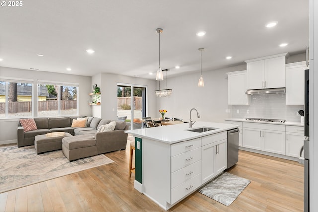 kitchen featuring sink, white cabinetry, stainless steel appliances, an island with sink, and decorative light fixtures