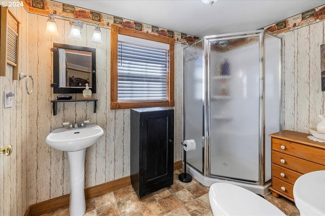 full bathroom featuring toilet, a stall shower, baseboards, and a sink