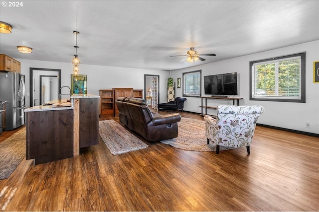 living area featuring ceiling fan, baseboards, and wood finished floors