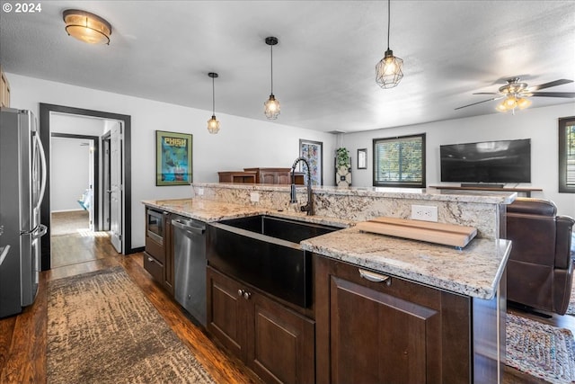 kitchen featuring a center island with sink, appliances with stainless steel finishes, pendant lighting, and a sink