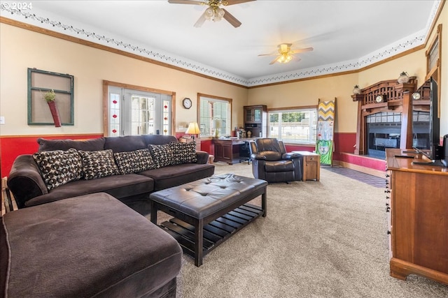 carpeted living room featuring a fireplace with raised hearth and ceiling fan