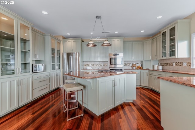 335 Runyan Rd, Woodland, WA 98674 - kitchen featuring dark wood-style flooring, appliances with stainless steel finishes, light stone countertops, a breakfast bar area, and recessed lighting