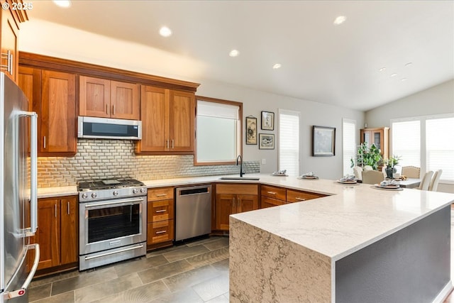 626 SE 38th Dr, Gresham, OR 97080 - kitchen with stainless steel appliances, a peninsula, brown cabinets, backsplash, and vaulted ceiling