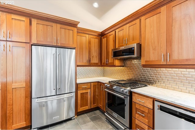 626 SE 38th Dr, Gresham, OR 97080 - kitchen with appliances with stainless steel finishes, brown cabinetry, light stone counters, decorative backsplash, and dark tile patterned flooring