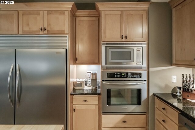 kitchen featuring dark stone counters, light brown cabinets, and built in appliances