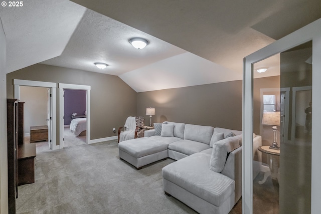 carpeted living area with a textured ceiling, baseboards, and lofted ceiling