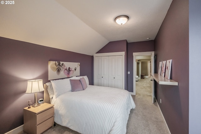 bedroom featuring vaulted ceiling, baseboards, a closet, and light carpet