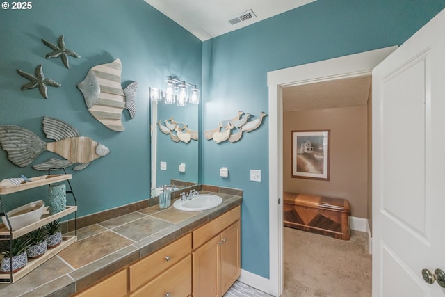 bathroom featuring visible vents, baseboards, and vanity