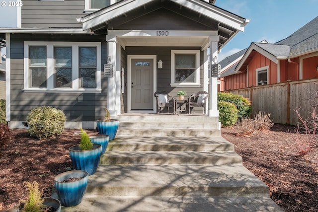 doorway to property featuring covered porch and fence