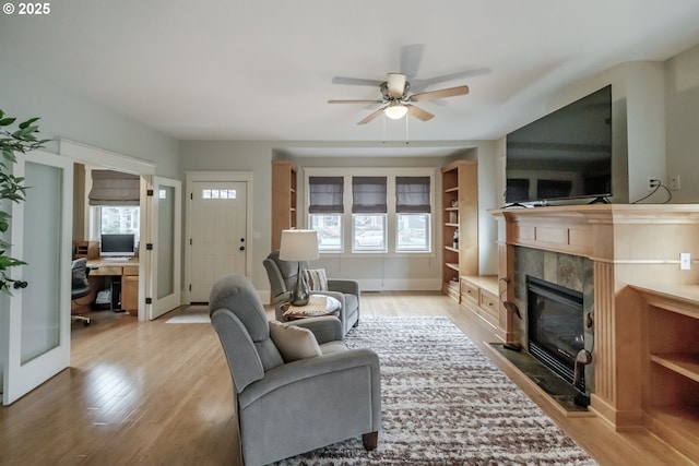 living area with ceiling fan, baseboards, wood finished floors, and a fireplace
