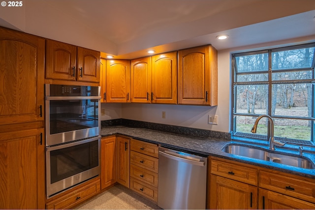 kitchen with a healthy amount of sunlight, appliances with stainless steel finishes, sink, and dark stone counters