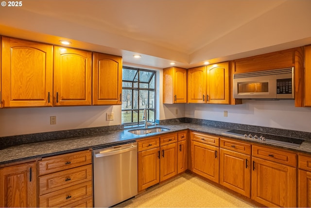 kitchen featuring lofted ceiling, appliances with stainless steel finishes, sink, and dark stone counters