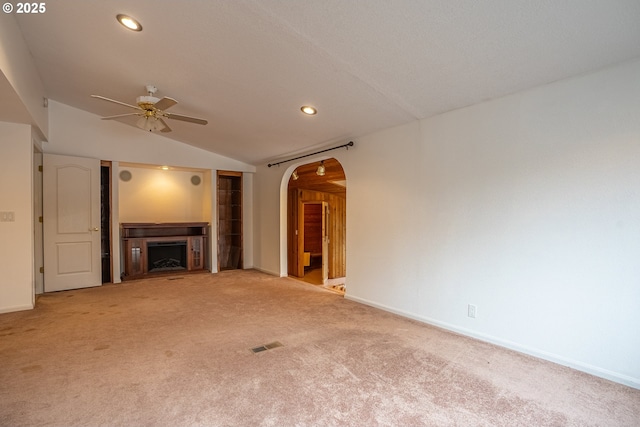 unfurnished living room with ceiling fan, lofted ceiling, and light carpet