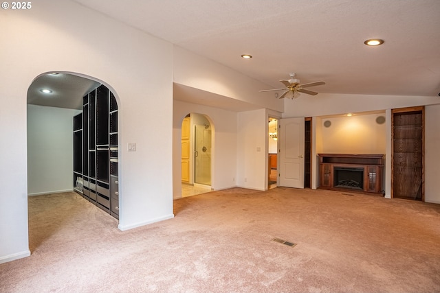 unfurnished living room featuring ceiling fan, vaulted ceiling, and light carpet