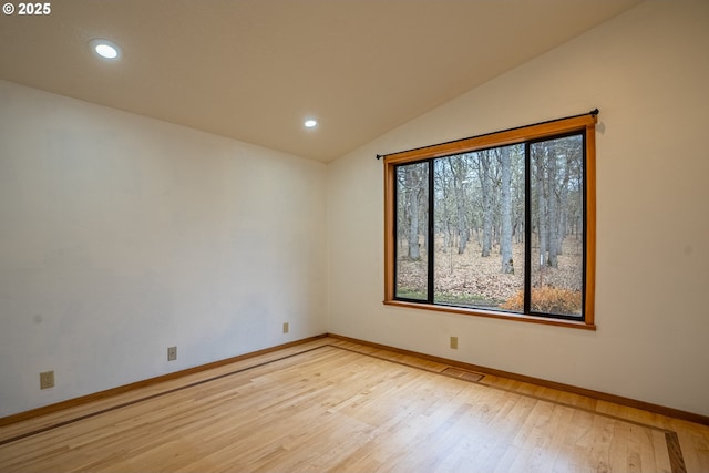 spare room featuring lofted ceiling and light hardwood / wood-style flooring