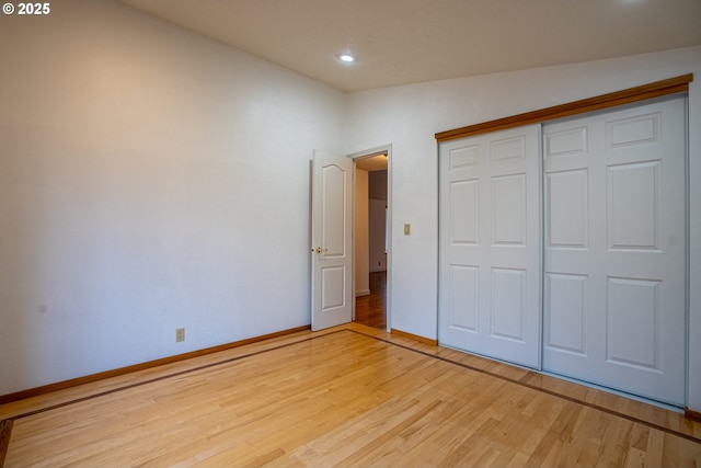 unfurnished bedroom with lofted ceiling, light hardwood / wood-style flooring, and a closet