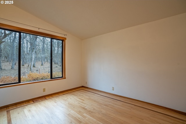 unfurnished room featuring vaulted ceiling and light hardwood / wood-style flooring