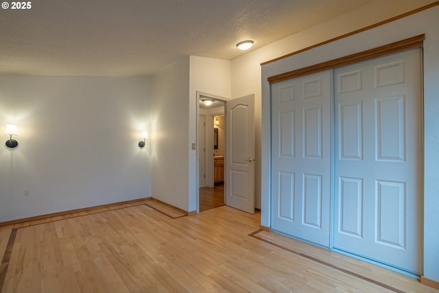 unfurnished bedroom with a closet, a textured ceiling, and light wood-type flooring