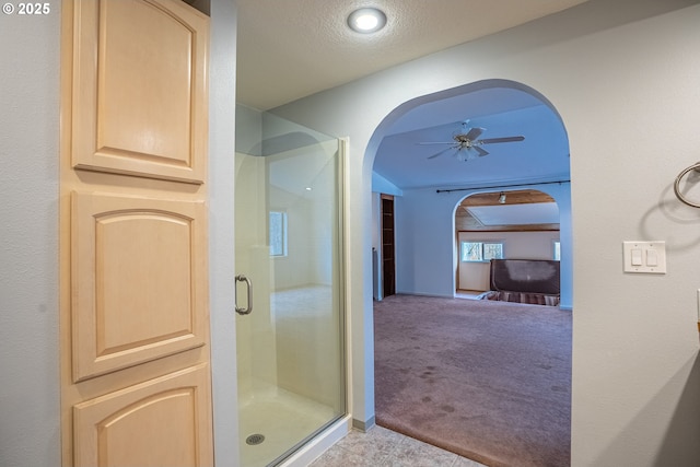 bathroom featuring lofted ceiling, a textured ceiling, ceiling fan, and walk in shower