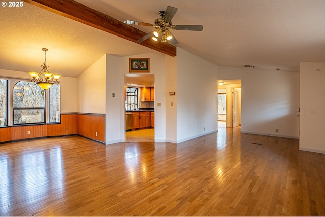 unfurnished room featuring lofted ceiling with beams, ceiling fan with notable chandelier, a textured ceiling, and light hardwood / wood-style floors