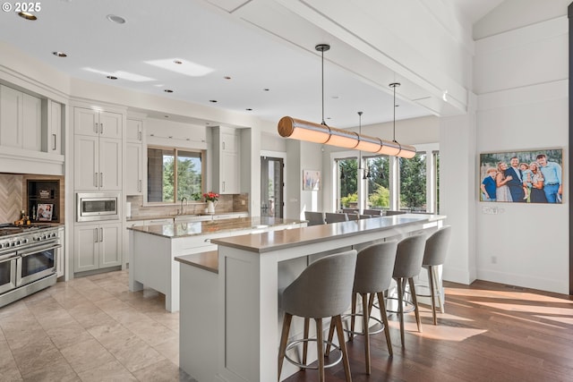 5390 NW Roanoke Ln, Portland, OR 97229 - kitchen featuring stainless steel appliances, a center island, decorative backsplash, a kitchen breakfast bar, and recessed lighting