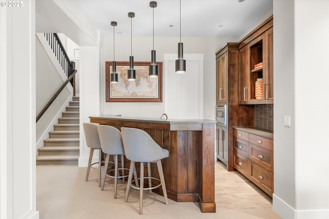 5390 NW Roanoke Ln, Portland, OR 97229 - indoor wet bar featuring stainless steel microwave, hanging light fixtures, stairs, and tasteful backsplash