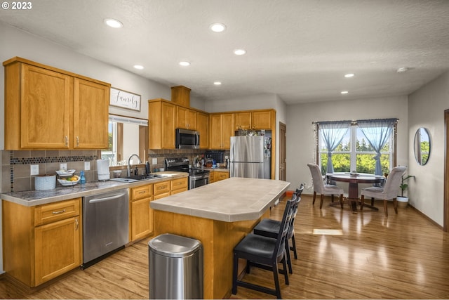 kitchen with appliances with stainless steel finishes, a sink, healthy amount of natural light, decorative backsplash, and recessed lighting