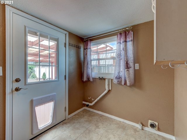 doorway with baseboards, a textured ceiling, and heating unit