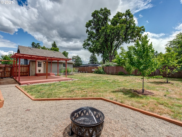 view of yard featuring a fenced backyard, a fire pit, an outbuilding, and a wooden deck