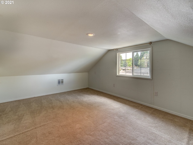 bonus room featuring carpet floors, lofted ceiling, visible vents, and a textured ceiling