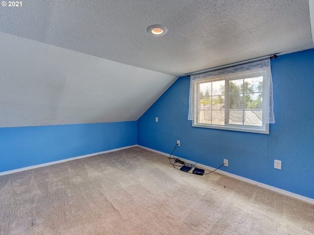 bonus room featuring lofted ceiling, carpet, baseboards, and a textured ceiling