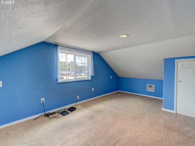 bonus room with carpet, visible vents, lofted ceiling, and a textured ceiling