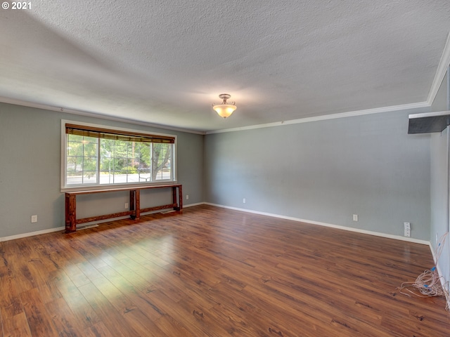 empty room featuring crown molding, dark wood finished floors, and baseboards