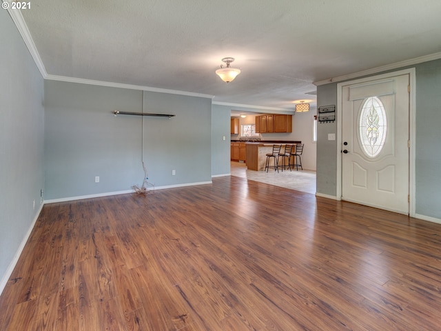 unfurnished living room featuring dark wood-style flooring, crown molding, and baseboards