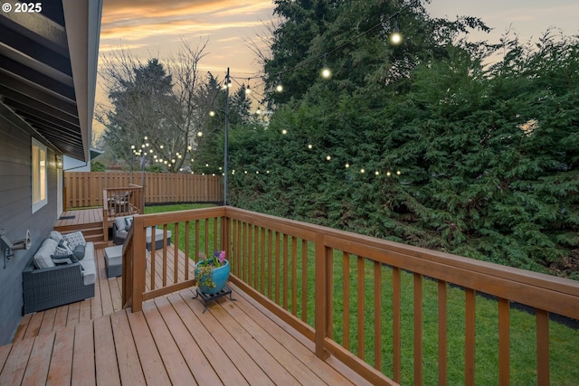 deck at dusk with a yard and fence