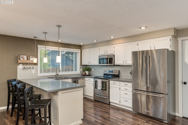 kitchen with a sink, decorative light fixtures, white cabinetry, appliances with stainless steel finishes, and a peninsula