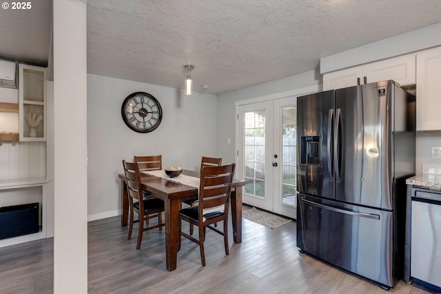 dining room featuring light wood-type flooring, a textured ceiling, and french doors