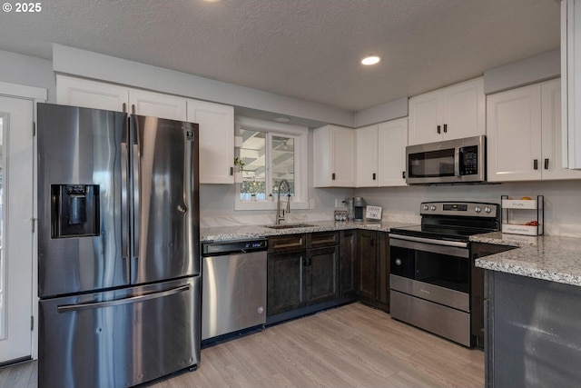 kitchen featuring light stone counters, sink, white cabinetry, and stainless steel appliances